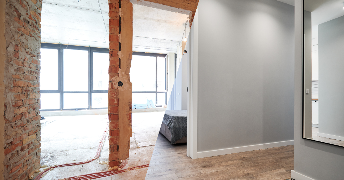 Interior of a house undergoing renovation with exposed brick wall and finished room next door