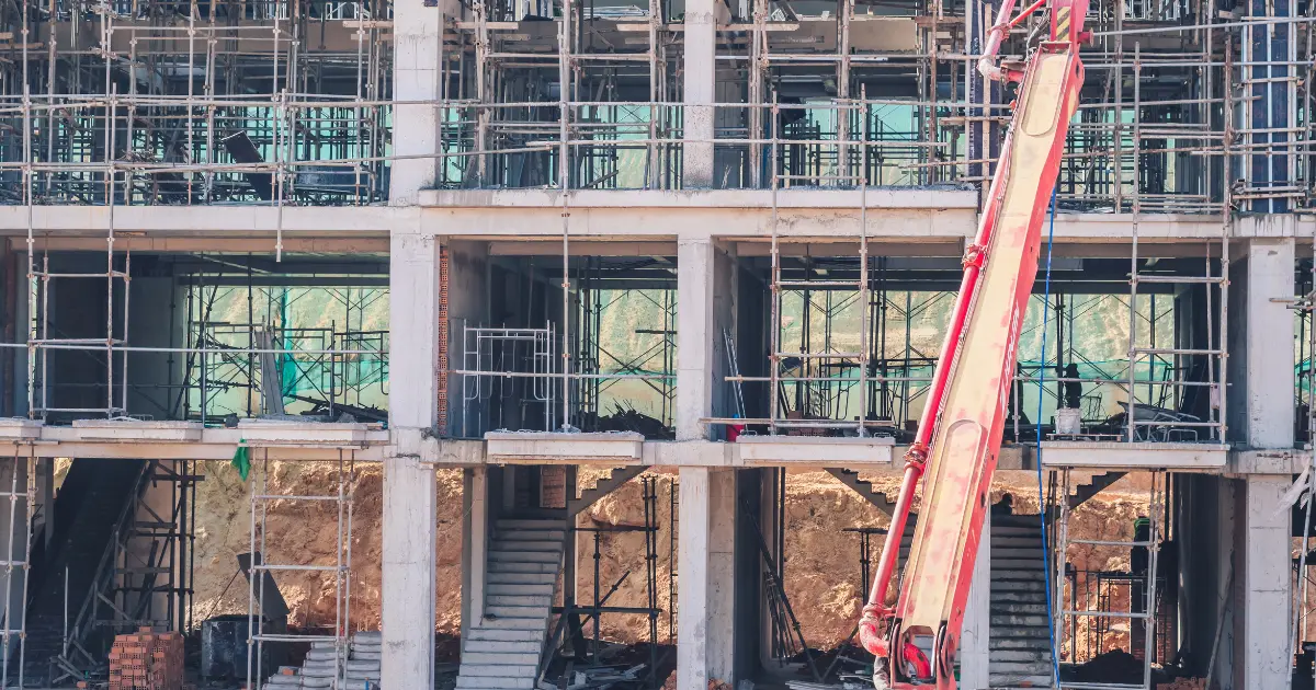 Building structure under construction with scaffolding, concrete pillars, and machinery during the early stages of construction