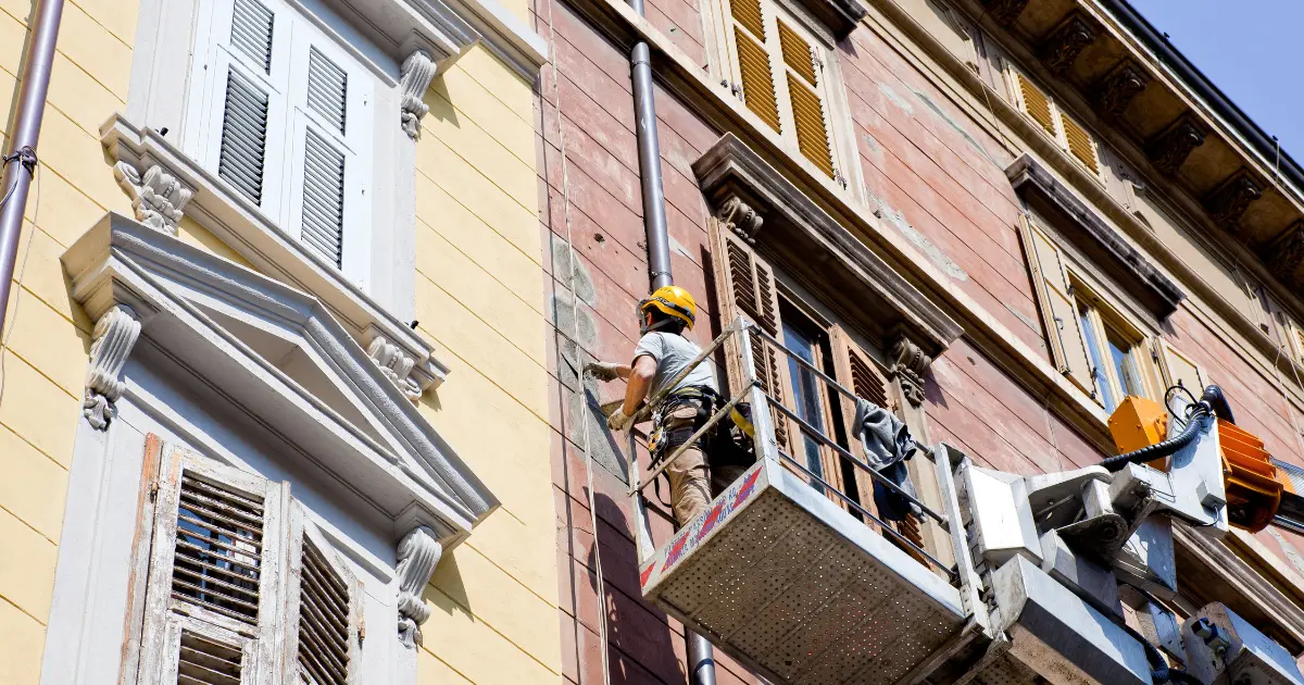 Worker working on the renovation of a building facade using a lifting platform