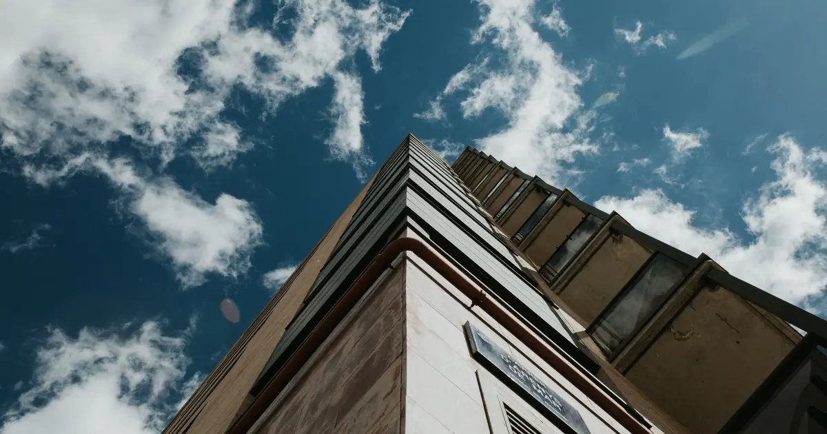 Vista en contrapicado de un edificio moderno en construcción, representando el proceso y el tiempo que conlleva levantar una edificación completa.