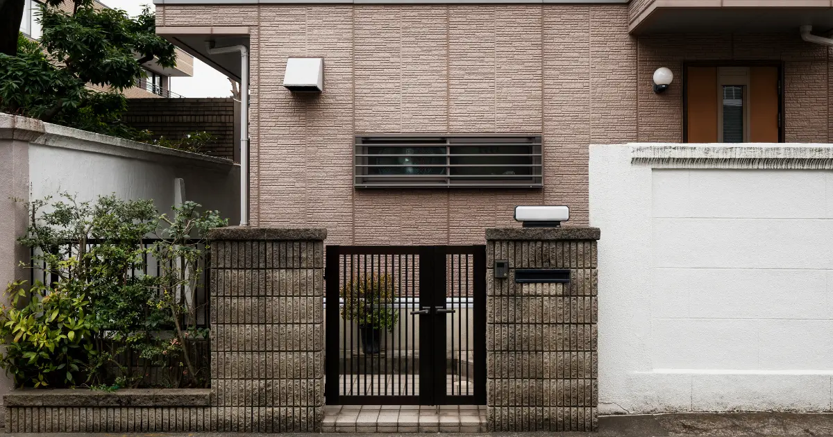 Muro medianero de una vivienda urbana con puerta metálica, ejemplo de cerramiento que debe respetar la altura legal entre propiedades vecinas.