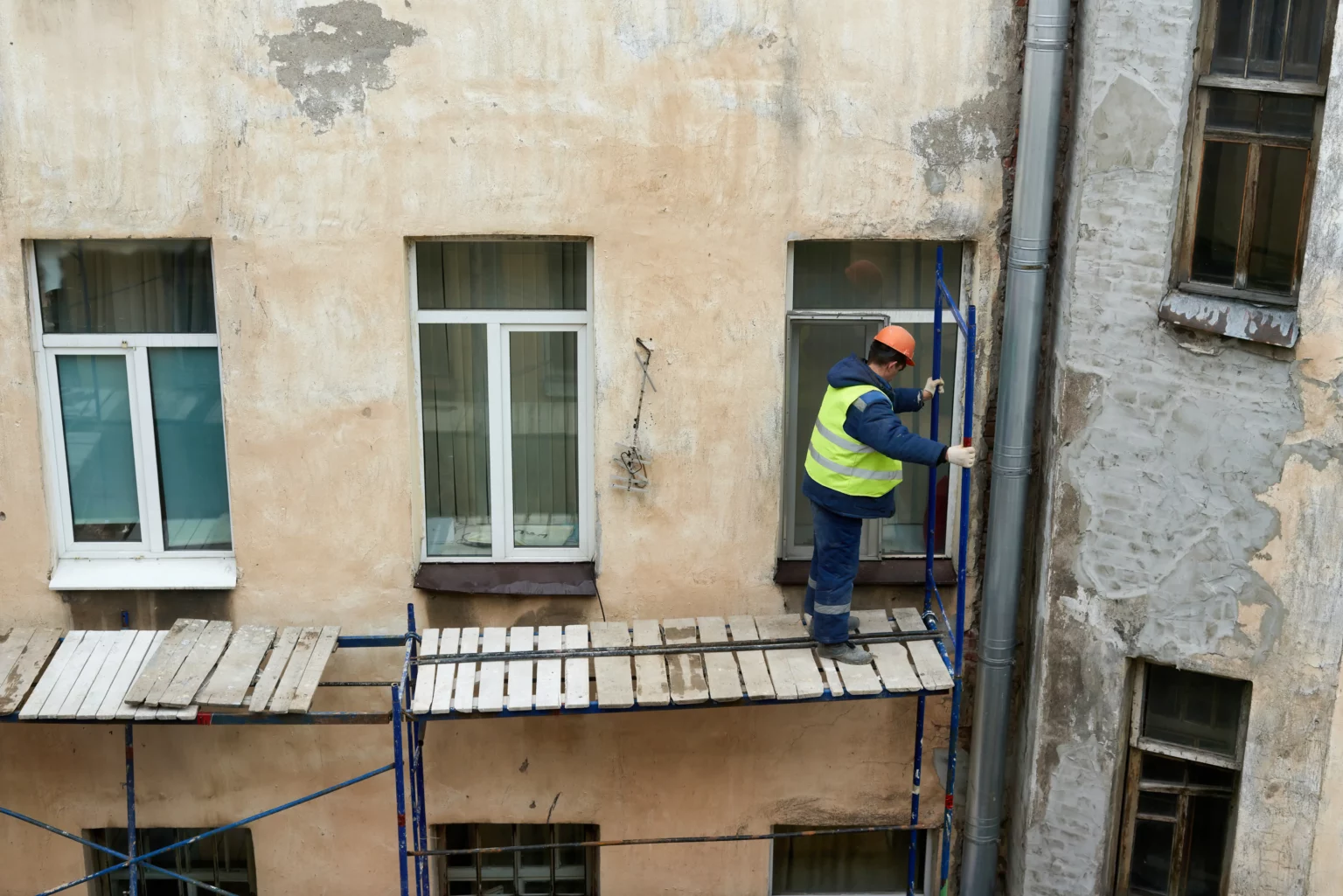 Construction worker assembling scaffolding to renovate the facade of a residential building