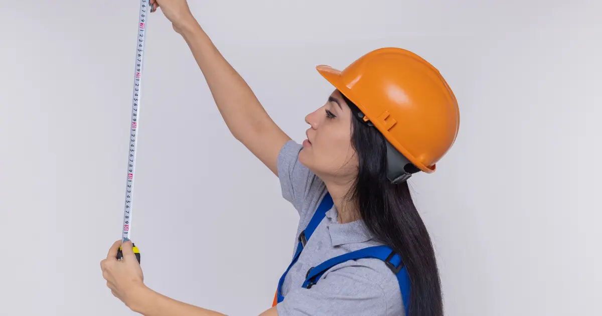 Girl wearing a helmet measuring a wall.