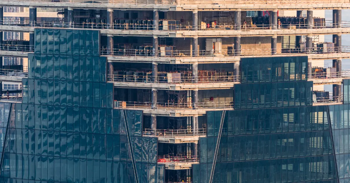 Edificio en construcción con estructura visible y fachada acristalada en proceso de obra