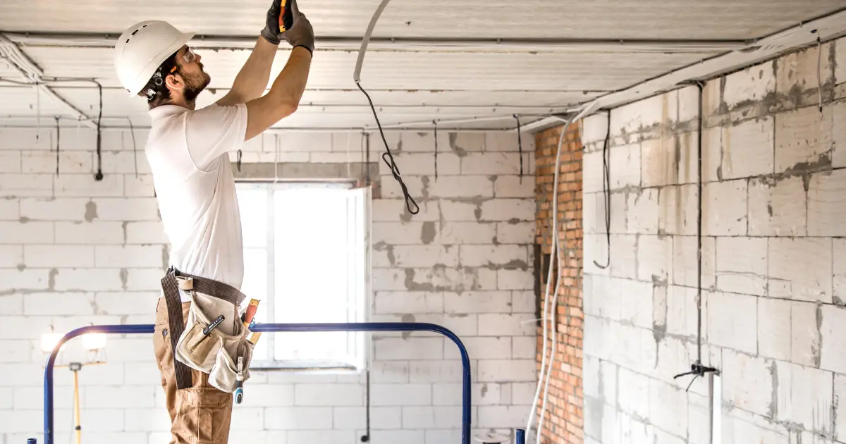 A technician performing electrical work on a construction site during a home renovation