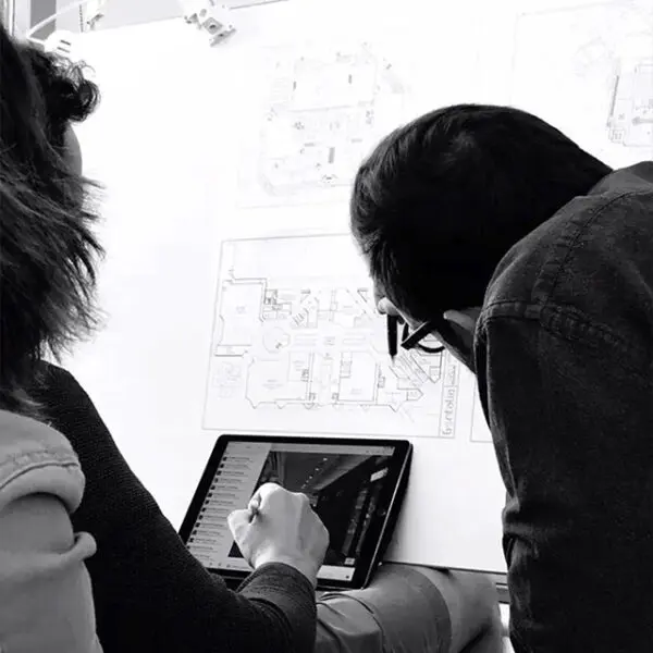 Equipo de arquitectos revisando planos y diseño en tablet durante proyecto de interiorismo