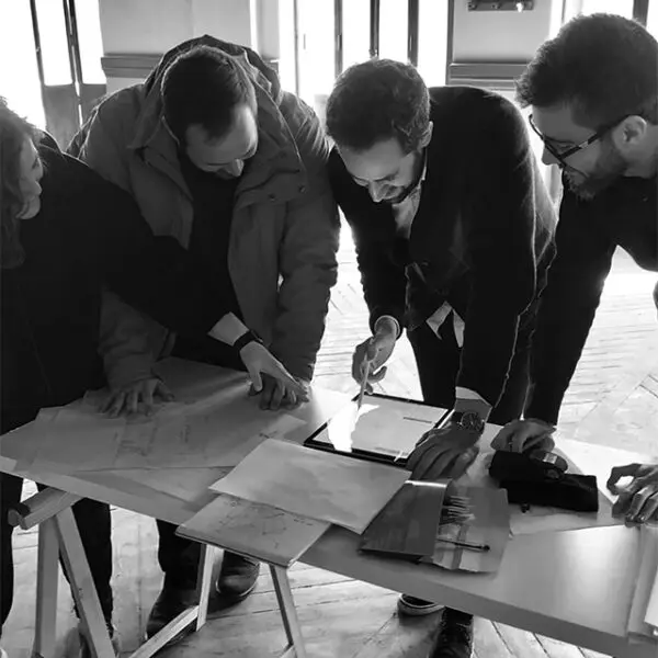 Equipo de arquitectos revisando planos y documentos técnicos en mesa de trabajo