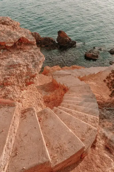Escalera de piedra junto al mar en entorno natural con costa rocosa