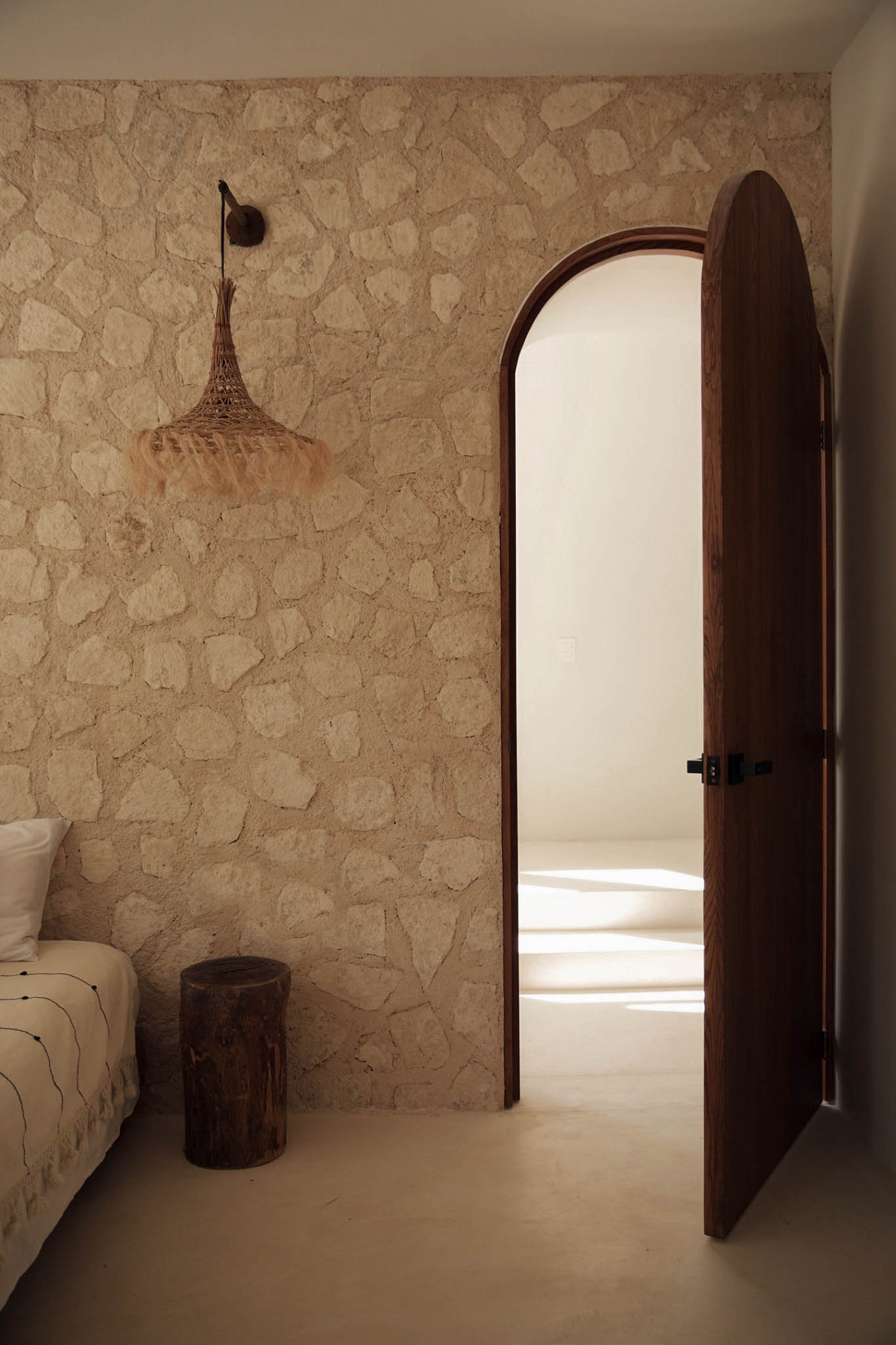 Interior en piedra natural con arco y puerta de madera en Ibiza
