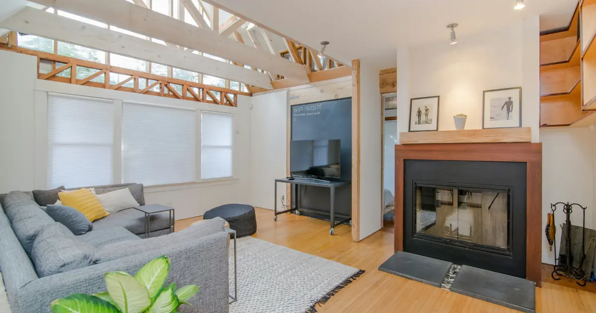 Salón moderno reformado con chimenea y techos de vigas vistas, ejemplo del resultado de una reforma integral de vivienda y del tiempo que puede requerir el proceso.