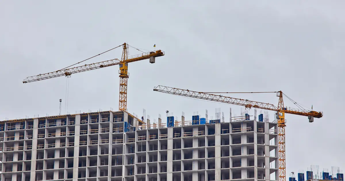 Edificio en construcción con grúas torre, ejemplo de proyecto que requiere la concesión de un permiso de obra por parte del ayuntamiento antes de iniciar los trabajos.