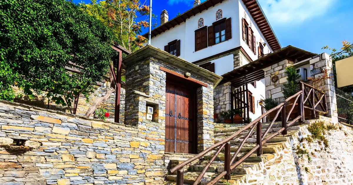 Muro perimetral de piedra en chalet con puerta de acceso y escaleras que delimitan la entrada a una vivienda unifamiliar